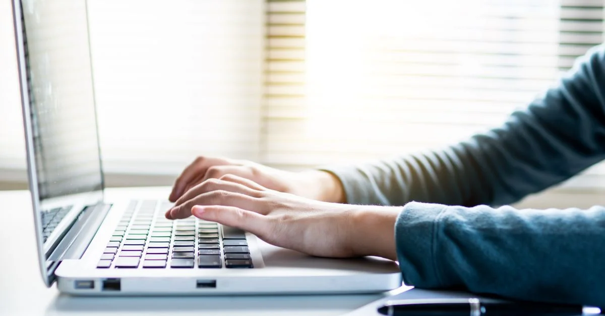 Gros plan des mains tapant sur un clavier d'ordinateur portable, parfait pour des thèmes d'affaires ou de technologie.