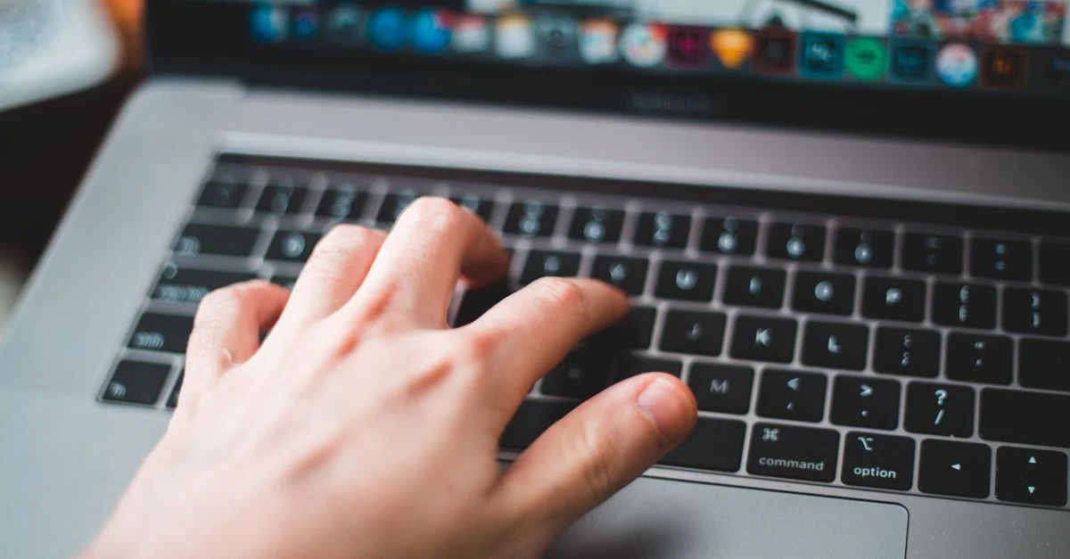 Gros plan sur une main tapant sur le clavier d'un ordinateur portable, mettant en avant la technologie moderne et le travail numérique.