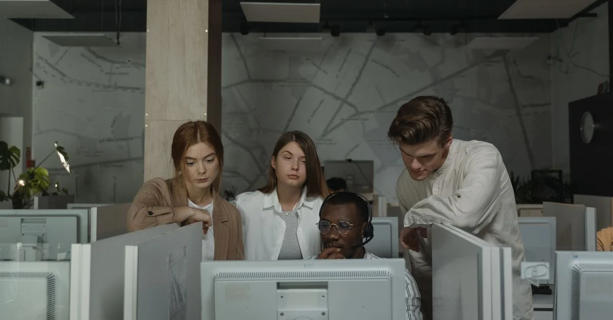 Équipe concentrée travaillant ensemble aux postes informatiques dans un environnement de bureau moderne.