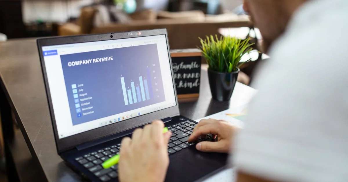 Homme utilisant un ordinateur portable pour analyser les données de revenus de l'entreprise avec des graphiques dans un bureau.
