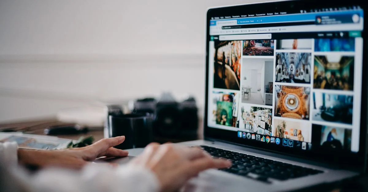 Gros plan sur des mains utilisant un ordinateur portable pour rechercher des images et parcourir une galerie de photos numériques.