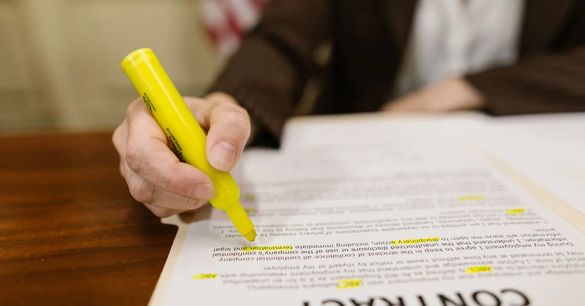 Un gros plan d'une main surlignant un contrat, mettant en avant des termes juridiques importants.