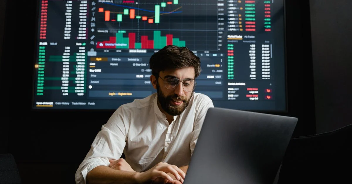Analyste masculin étudie les tendances des cryptomonnaies à un poste de travail avec plusieurs écrans affichant des données de marché.