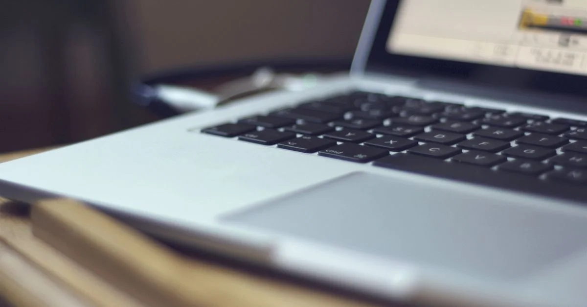 Image centrée d'un clavier d'ordinateur portable sur une table à l'intérieur, montrant la technologie moderne.
