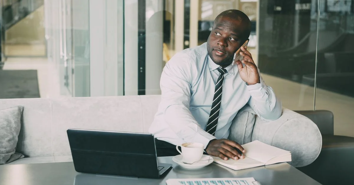 Homme d'affaires adulte dans la salle de repos de son bureau, utilisant son ordinateur portable et son smartphone avec un café.